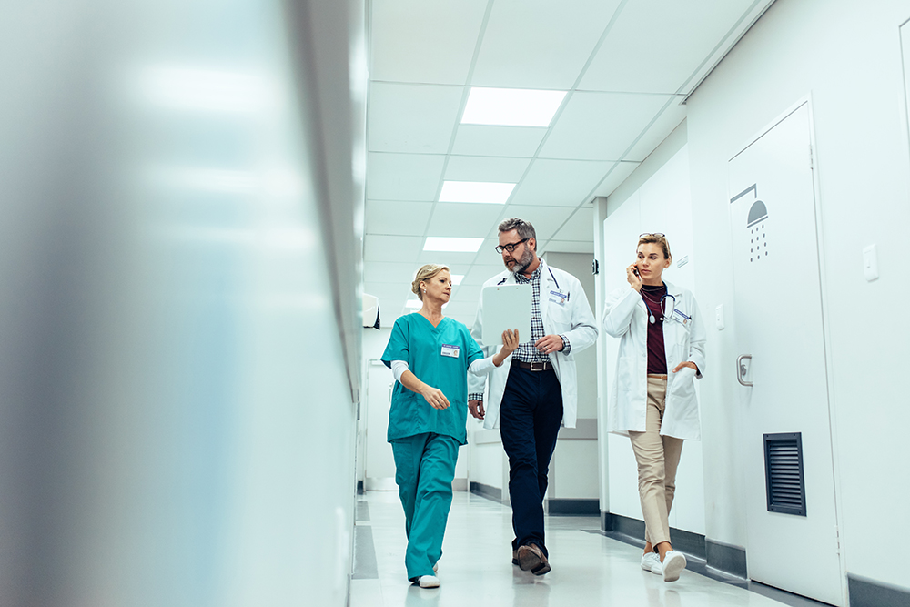 Doctor and nurse briefing medical report with female colleague talking on mobile phone.
